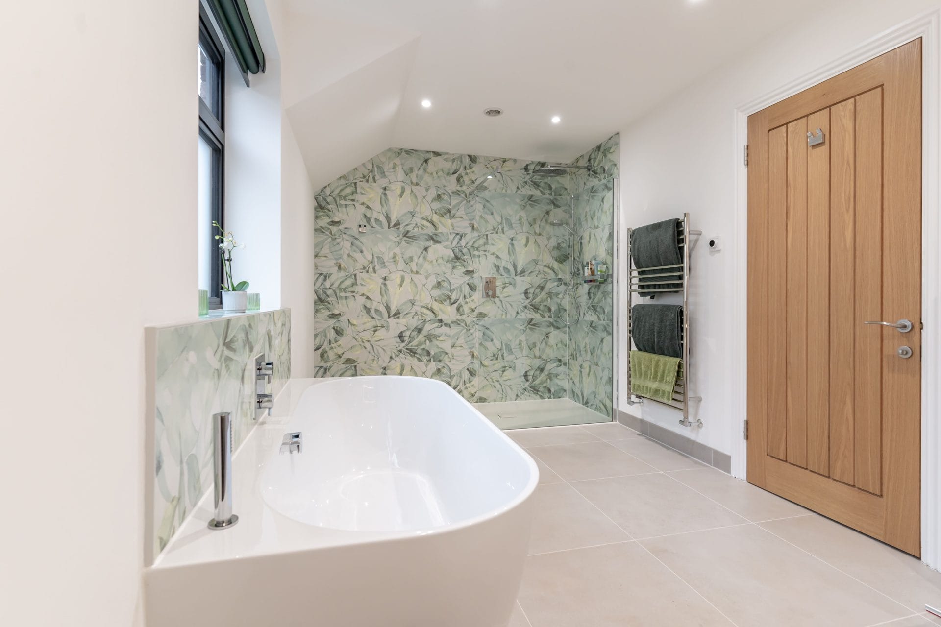 Walk-in shower with botanical print tiles and freestanding bath in a bathroom renovation