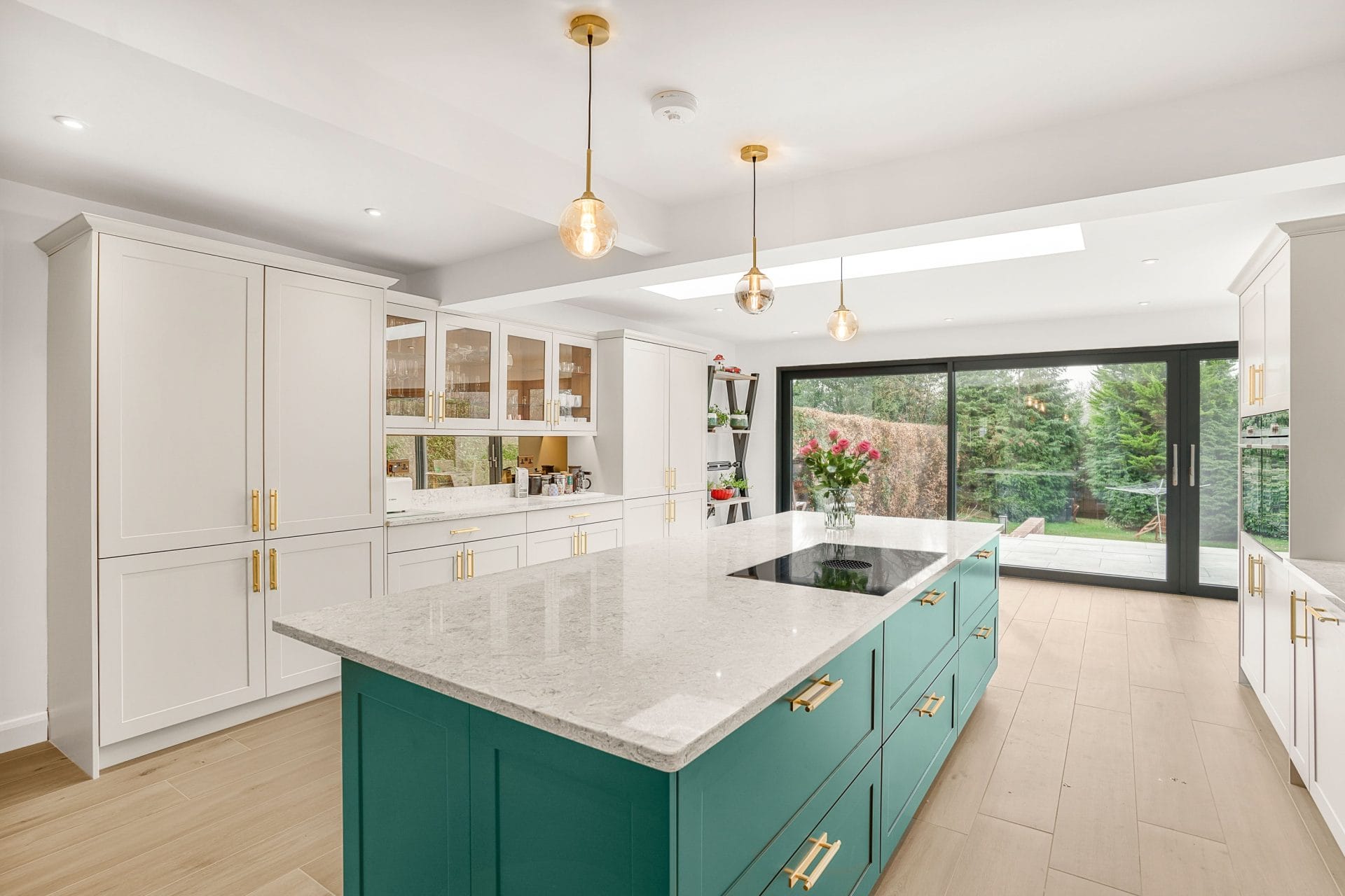 Teal kitchen island with quartz worktop and white shaker units in a modern German kitchen