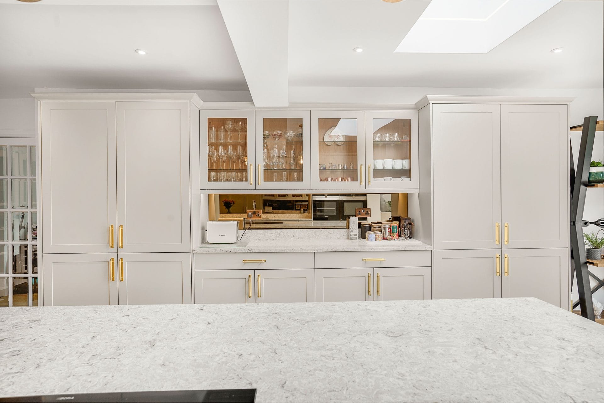 Classic shaker kitchen with light grey cabinetry, brass handles and marble-effect worktops