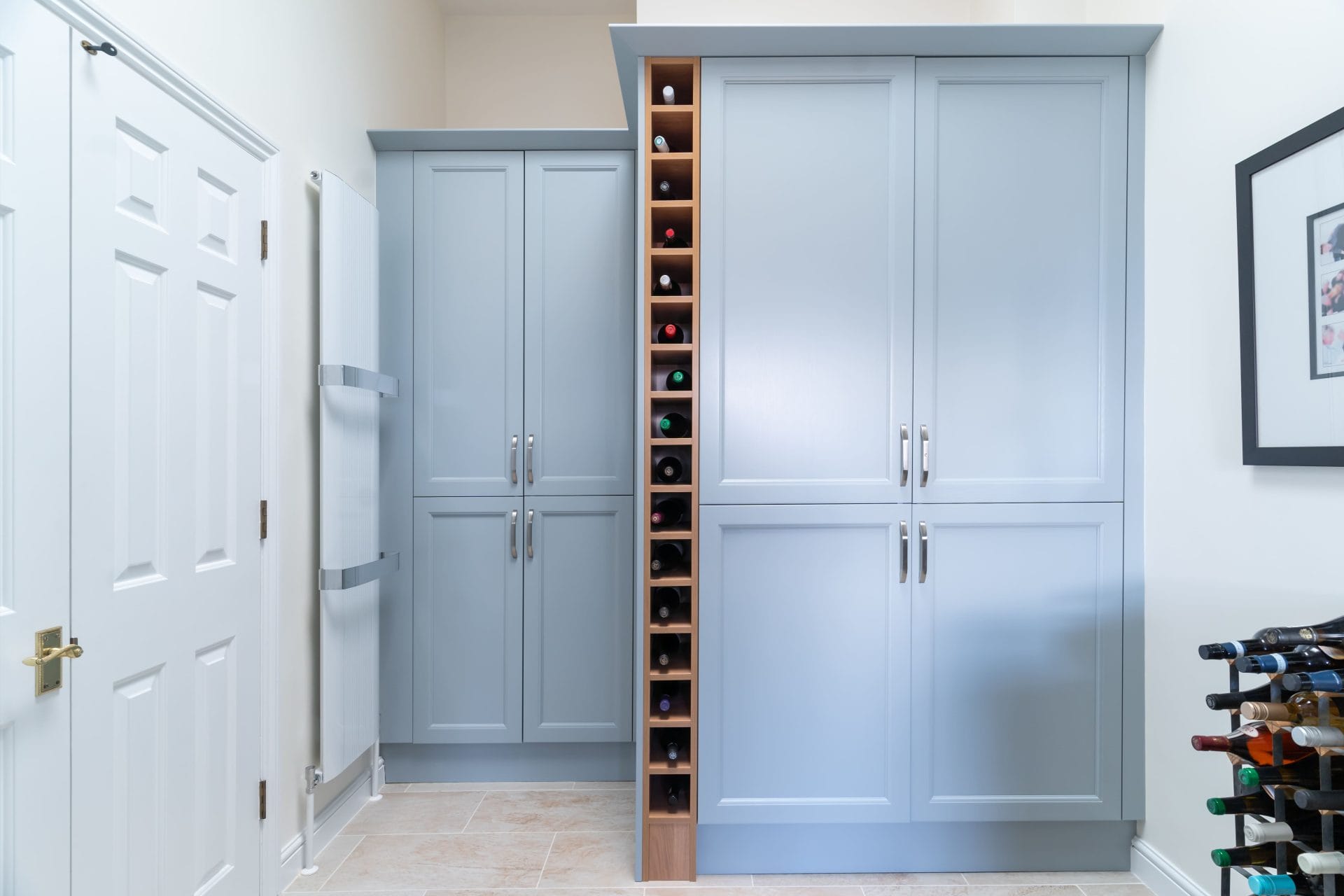 Light blue utility room cabinets with integrated wine rack and tall radiator